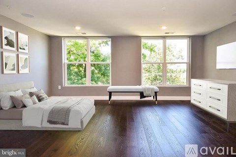 A bedroom with a large bed and a bench in front of a window.