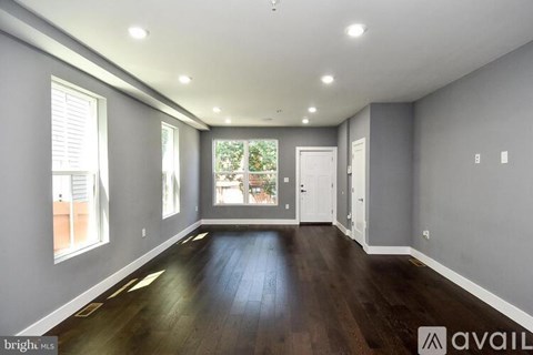 A spacious room with wooden floors and white walls.