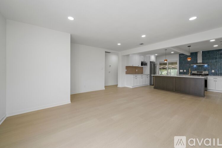 A spacious room with wooden flooring and white walls.
