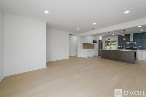 A spacious room with wooden flooring and white walls.