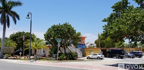 A street view with cars, trees, and a building with a sign that reads "AVON".