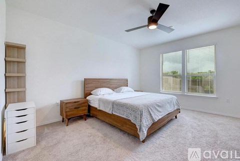 A bedroom with a bed, nightstand, and a fan.