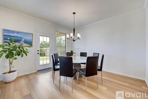 A dining room with a table set for four and a plant in a white pot.