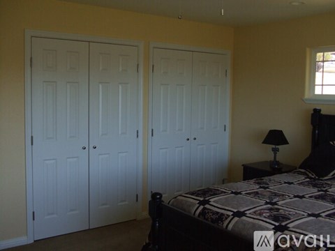 A bedroom with a bed, two doors, and a lamp.