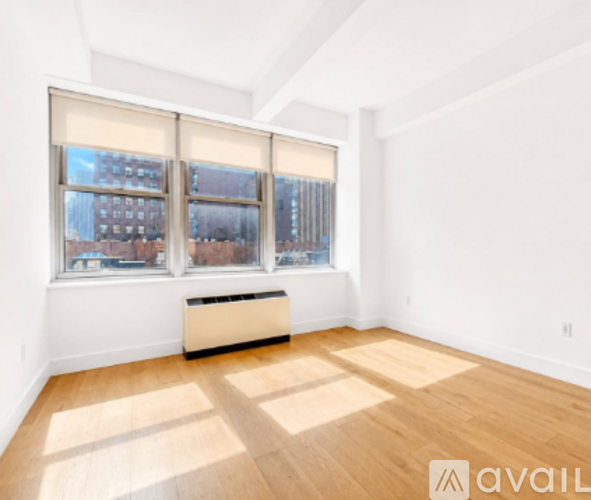 A room with wooden floors and a window with blinds.