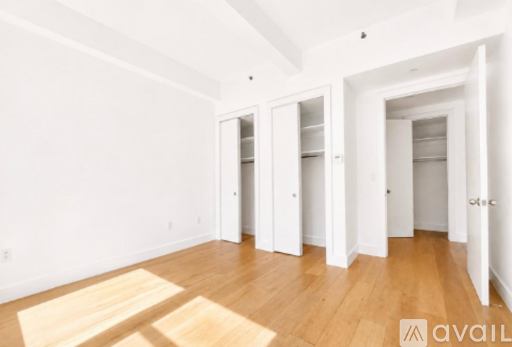 A room with white walls and wooden flooring, with a few doors and a sign that says "available".