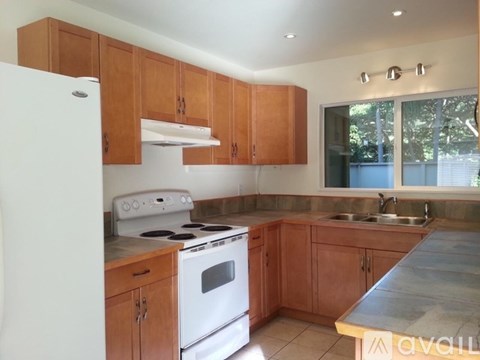 A kitchen with wooden cabinets and a white stove top oven.