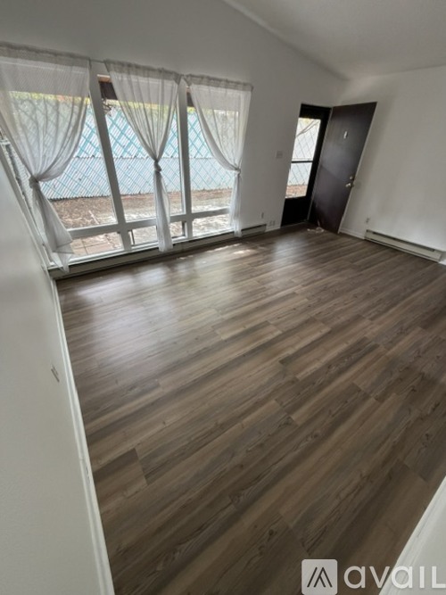 A room with wooden flooring and a view of a pool through the window.