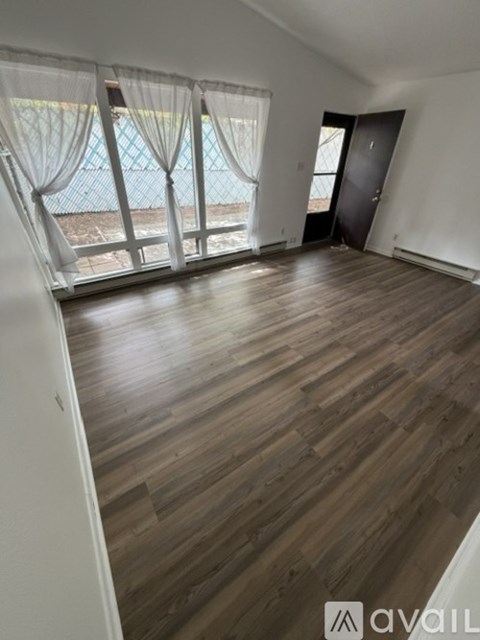 A room with wooden flooring and a view of a pool through the window.