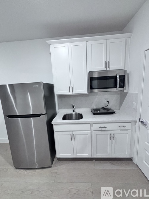 A kitchen with white cabinets and a stainless steel refrigerator.