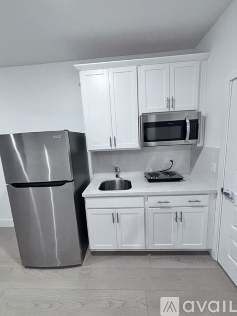A kitchen with white cabinets and a stainless steel refrigerator.