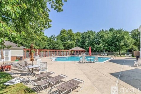 A large outdoor pool area with lounge chairs and a gazebo.