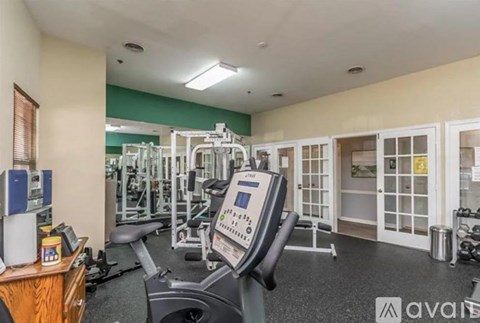 A gym with a variety of equipment including treadmills, weights, and exercise machines.