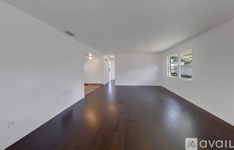A spacious room with wooden floors and white walls.