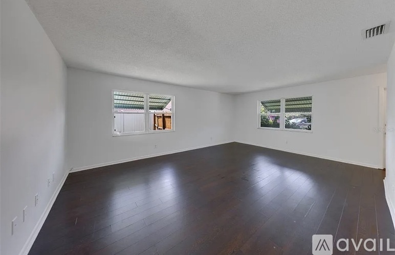 A room with wooden floors and two windows.