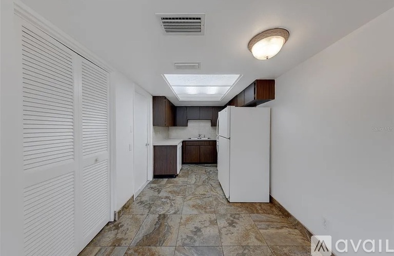 A kitchen with white cabinets and a marble floor.