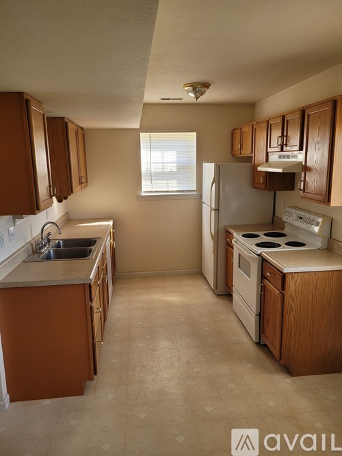 A kitchen with brown cabinets and a white fridge.