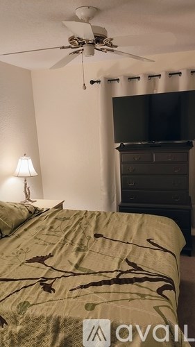 A bedroom with a bed, a ceiling fan, and a dresser.