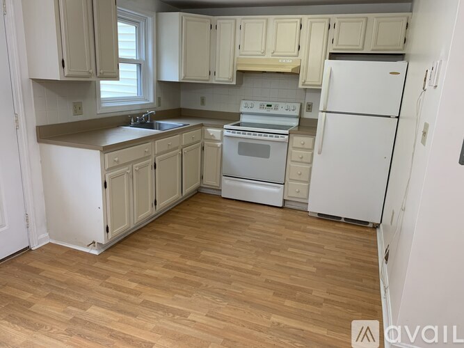 A kitchen with wooden floors and white appliances.
