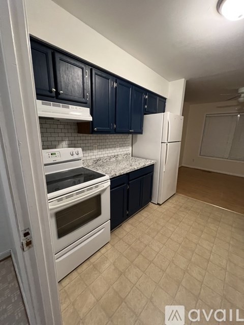 A kitchen with white appliances and dark blue cabinets.