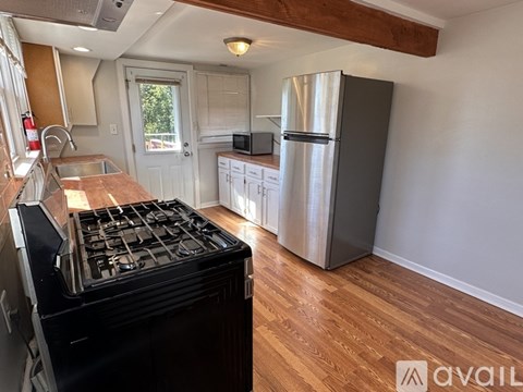 A kitchen with a black stove top oven and a silver refrigerator.