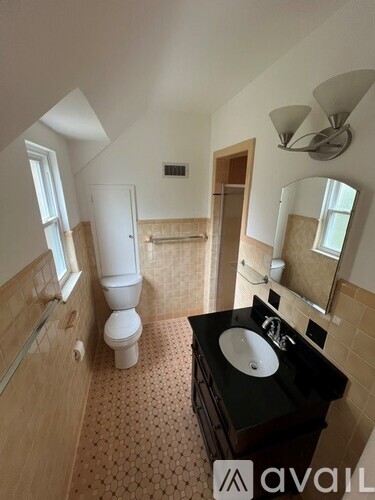 A bathroom with a toilet, sink, and mirror.