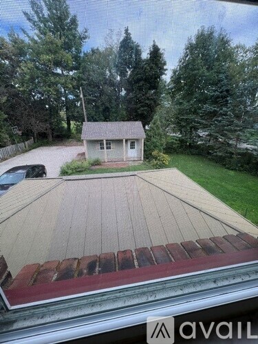 A house with a brown roof and a white door is surrounded by trees.