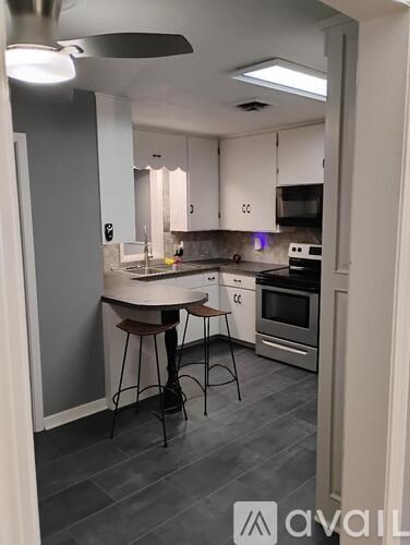 A kitchen with white cabinets and a table with two stools.