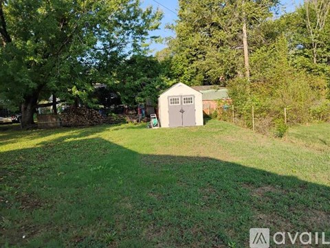 A shed sits in a grassy area with trees in the background.