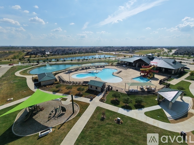 A large outdoor swimming pool surrounded by a grassy area and a playground.