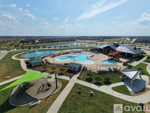 A large outdoor swimming pool surrounded by a grassy area and a playground.