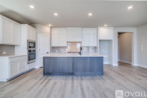 A modern kitchen with white cabinets and a wooden floor.