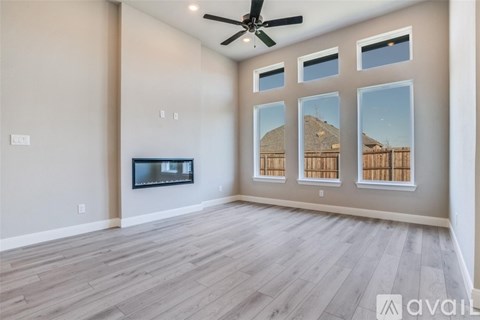 A spacious living room with a television and a ceiling fan.