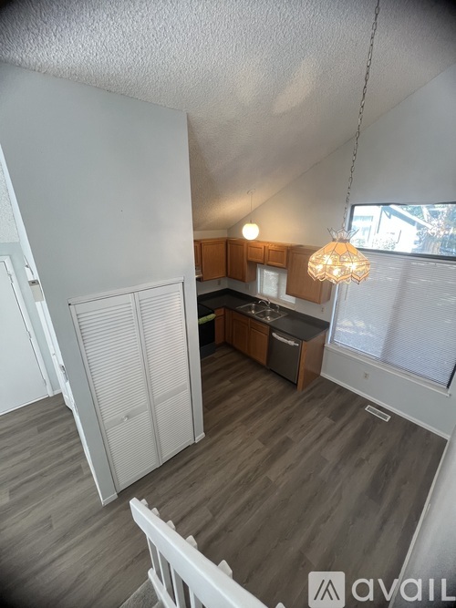 A kitchen with a white chair and wooden cabinets.