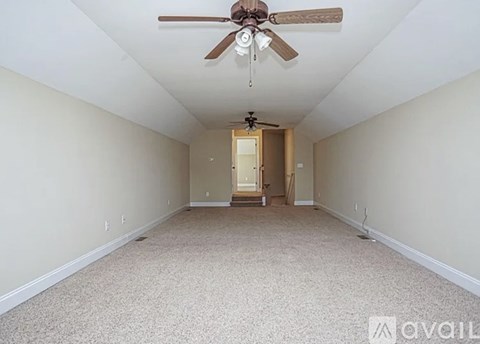 A spacious room with a ceiling fan and carpeted floor.