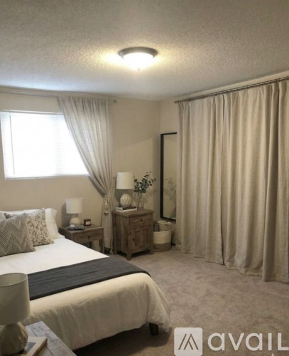 A bedroom with a large bed and a nightstand with a lamp.