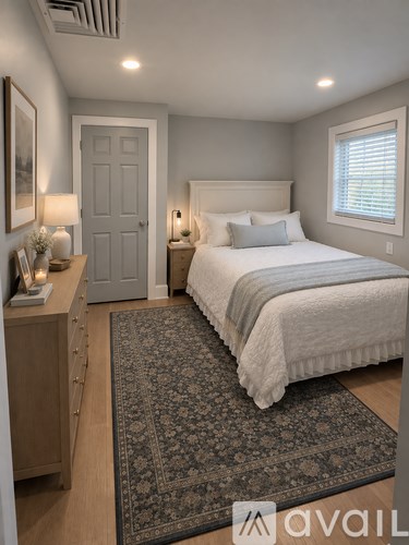 A bedroom with a large bed and a rug on the floor.