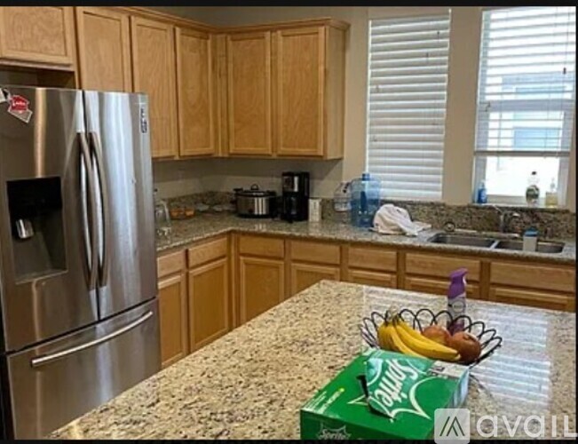 A kitchen with a stainless steel refrigerator and wooden cabinets.