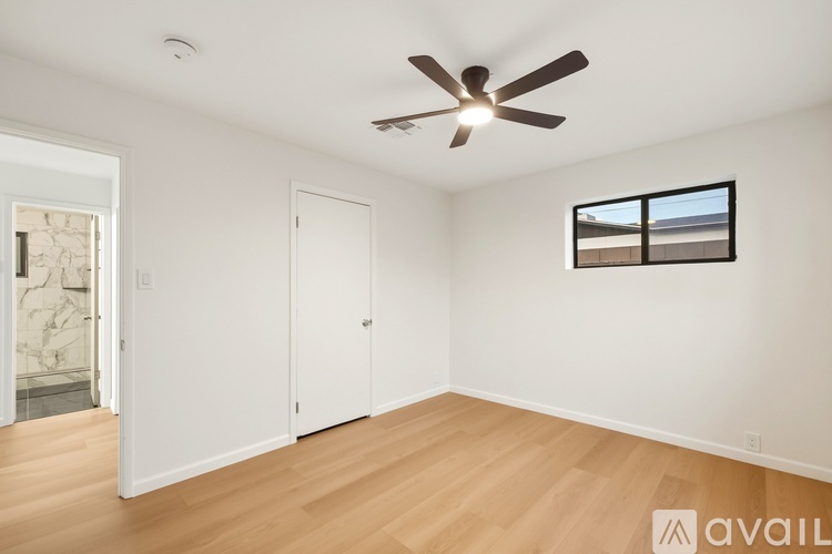 A room with a ceiling fan and a window with a view of a building outside.