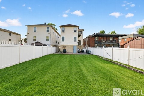 A large grassy area in front of a row of houses with a fence separating them.