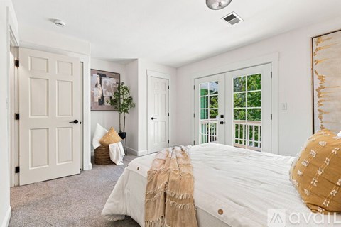 A bedroom with a large bed and a window with a view of trees.