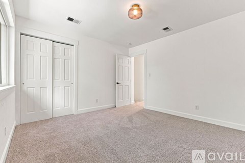 A spacious room with white walls and a carpeted floor.
