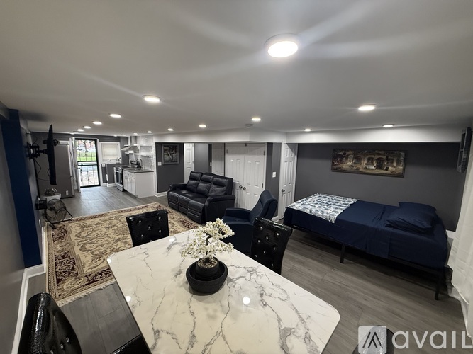 A living room with a marble table and a bed in the background.