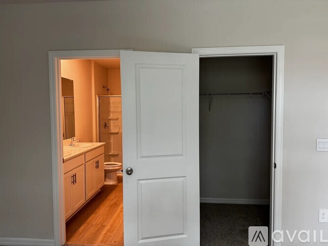 A white door is open to a bathroom and a bedroom.