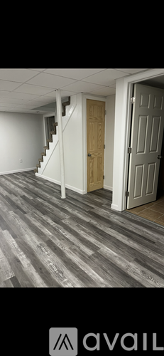 A room with wooden flooring and a staircase leading to another room.