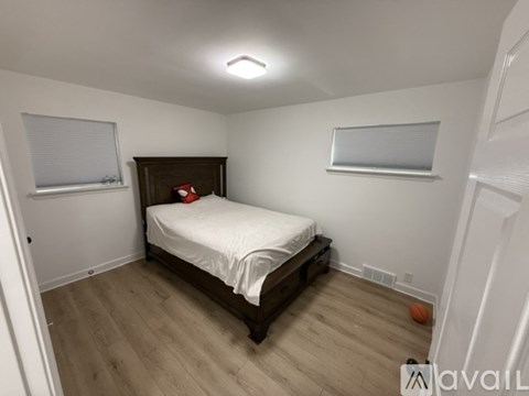 A bedroom with a bed, wooden headboard, and a window with blinds.