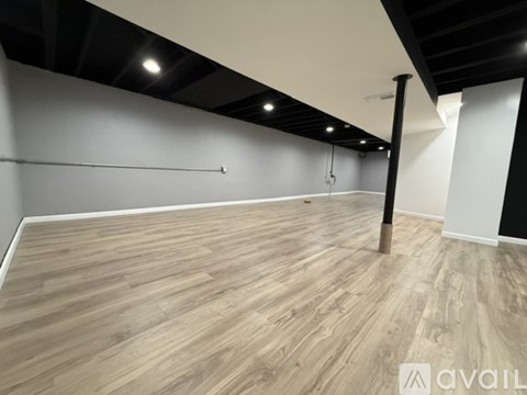 A spacious room with wooden flooring and a long white wall.