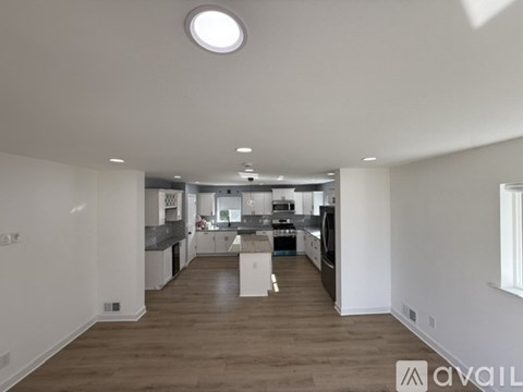 A spacious kitchen with white cabinets and a wooden floor.