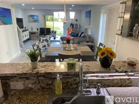 A kitchen with a marble countertop and a dining table set with sunflowers.