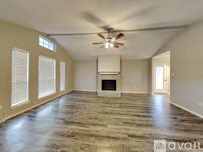 A spacious living room with a fireplace and a ceiling fan.